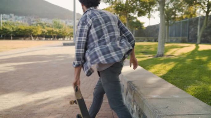 一个年轻人在手机上打字后骑着滑板在公园的人行道上