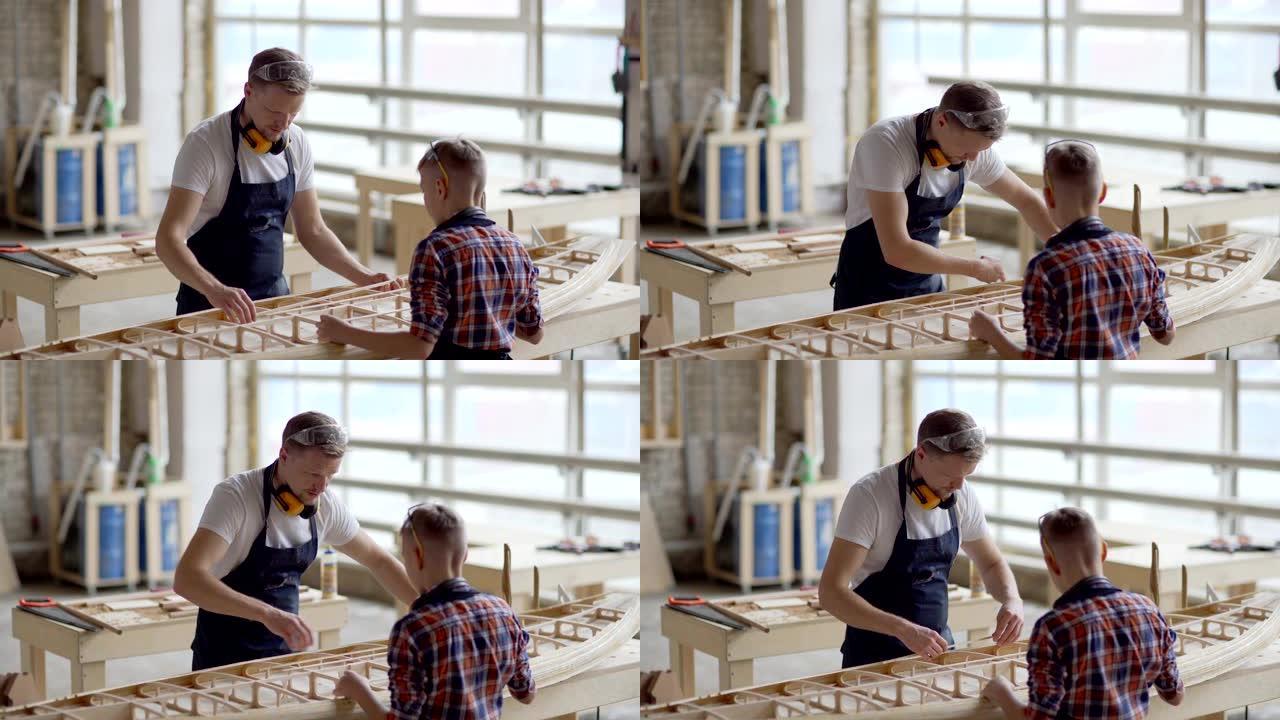 父子俩一起建造小木船，站在木工车间的工作台上。木匠教孩子如何放置木板
