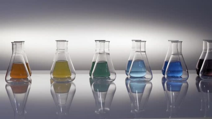 空的和混合的彩色液体填充的锥形瓶反射在桌子上