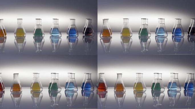 空的和混合的彩色液体填充的锥形瓶反射在桌子上