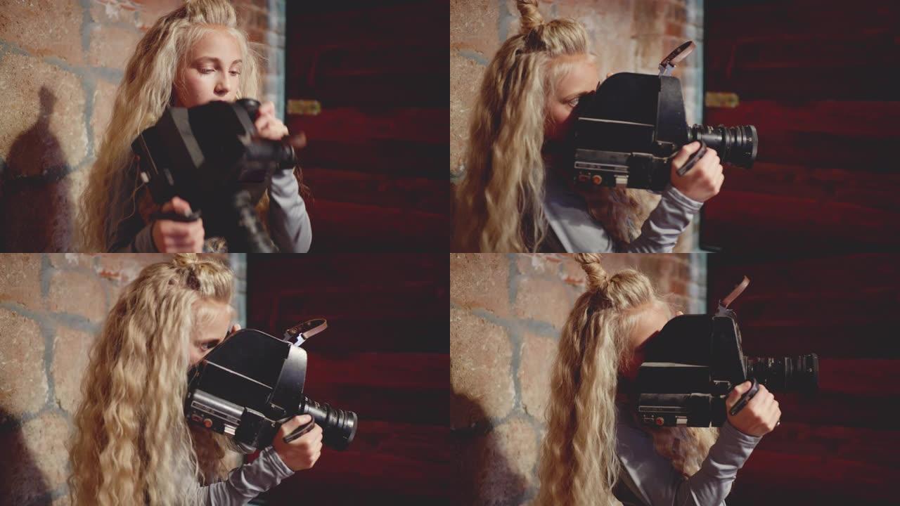 年轻女孩摄影师在布里克工作室用复古相机拍摄视频。女孩视频操作员在砖背景的艺术工作室用老式相机拍摄电影