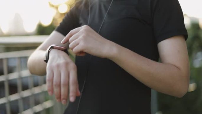 迷人的白人女运动员在城市日落时站在街道旁慢跑后，使用智能手表检查心率监测器跑步。