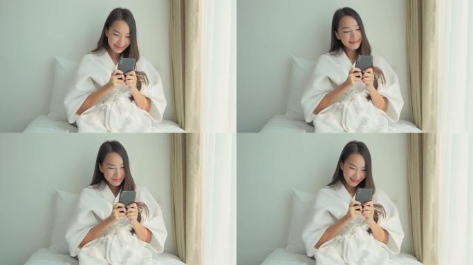 年轻的亚洲妇女在床上使用手机智能手机