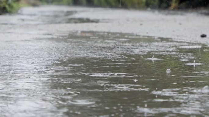 缓慢运动的雨滴落入水坑中，水溅起