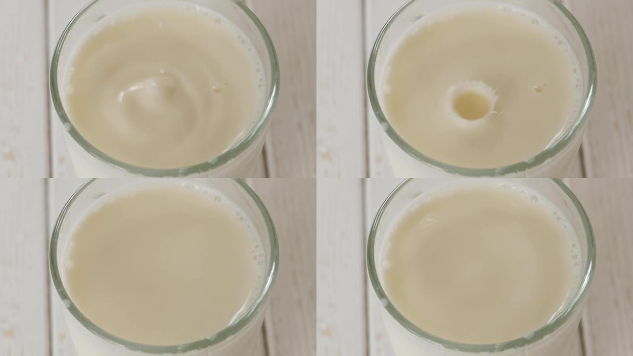 牛奶滴的特写镜头掉入一整杯牛奶中的轻木面