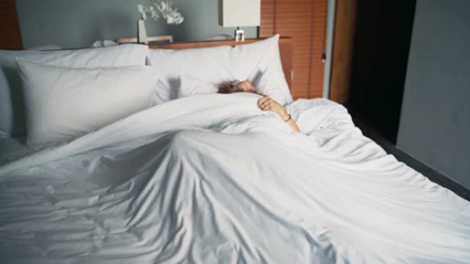 一个年轻的白人妇女不安地睡在床上。