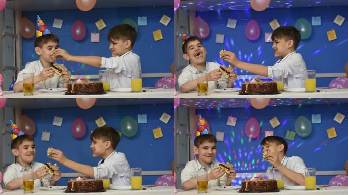 两个被弄脏的男孩在节日餐桌上有趣地吃蛋糕