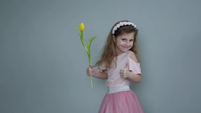 背景上有春天花束的小女孩。抱着黄色郁金香给妈妈的蹒跚学步的小女孩。8 3月或母亲节概念