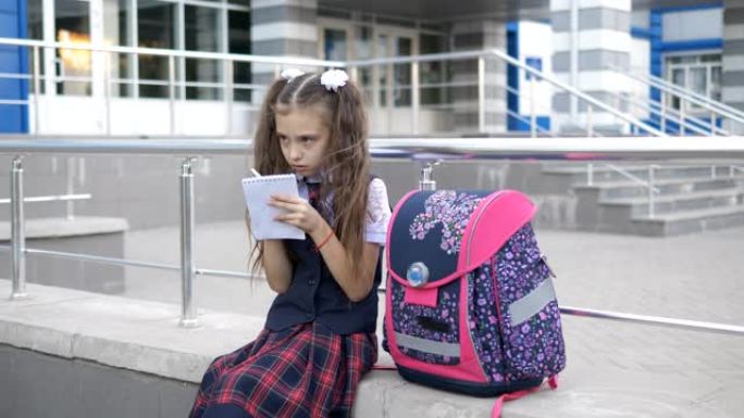 小女孩在大楼外写作业。放学后自学课。回到学校的概念。