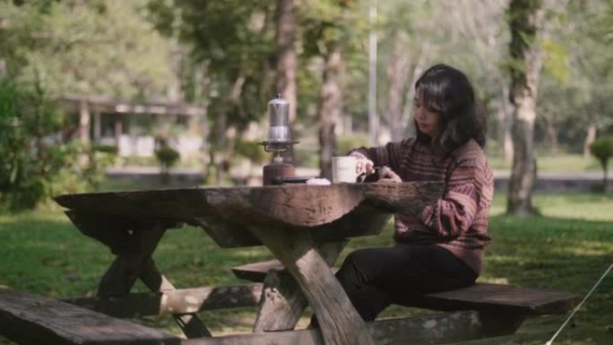 亚洲女孩用手动咖啡研磨机研磨咖啡豆，在美好的一天放松。