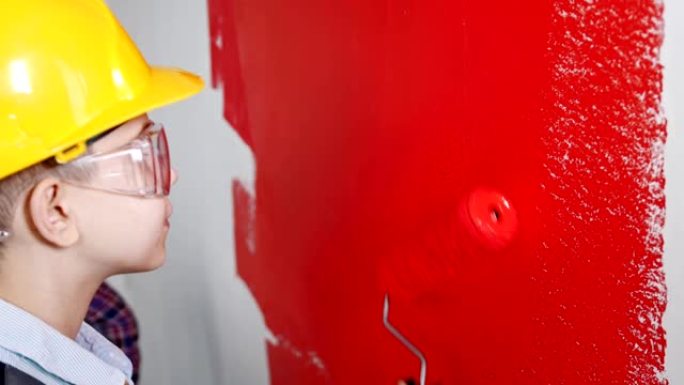 一个小男孩用红色油漆画透明的墙壁
