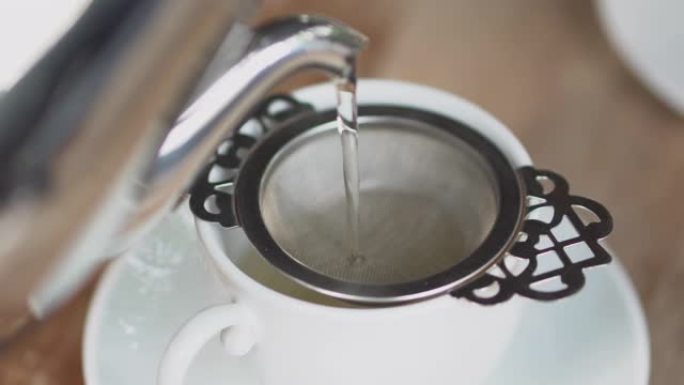 特写: 将水壶中的茶倒入一杯茶中 (将滤茶器提起)