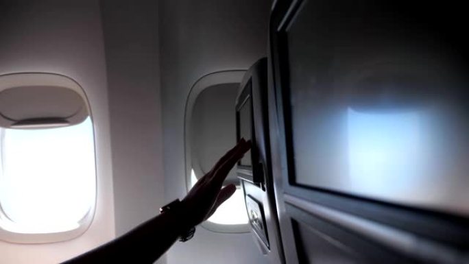 女人的手触摸飞机特写镜头中的座椅靠背屏幕
