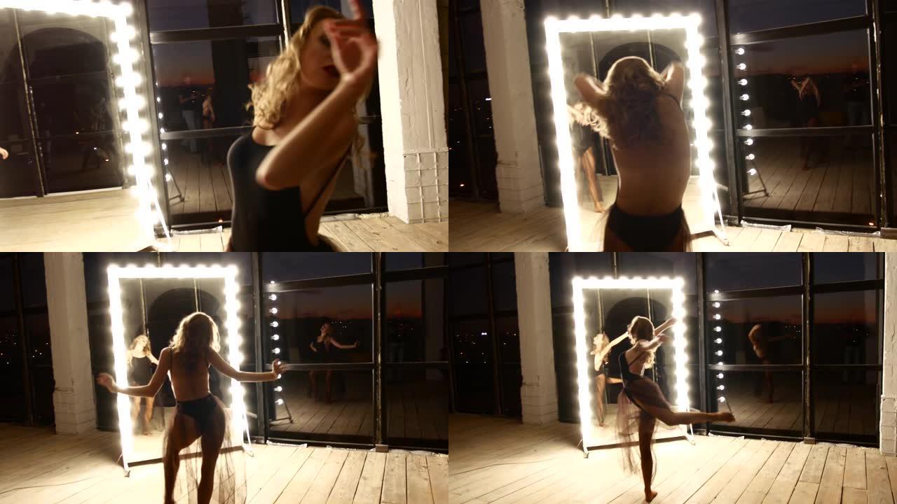 一个穿着紧身衣和裙子的漂亮女孩正在一个带灯泡的大镜子旁跳舞。perfomer正在黑暗的房间里训练