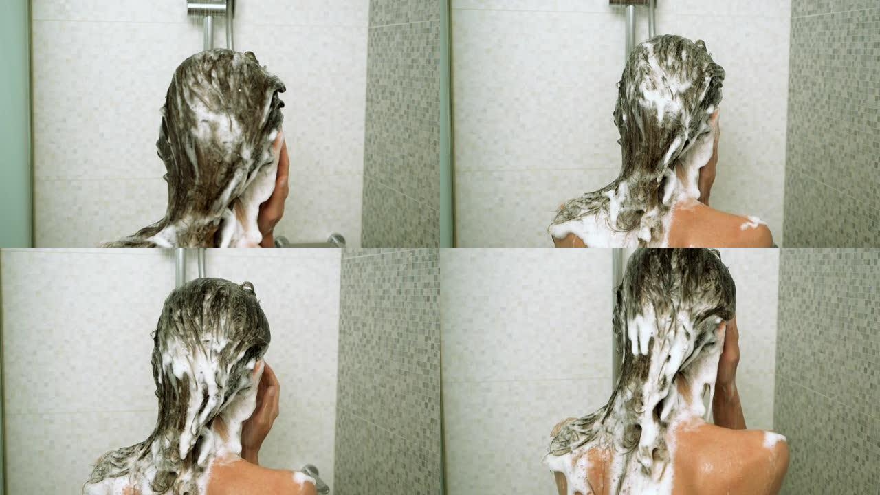 黑发苗条的女人洗她的头发用洗发水在淋浴。后面的特写镜头。缓慢的运动。高清