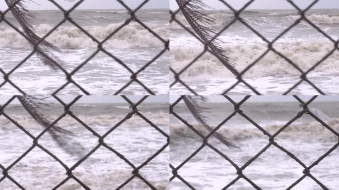靠近生锈的链节围栏的汹涌大海和大浪的机架焦点