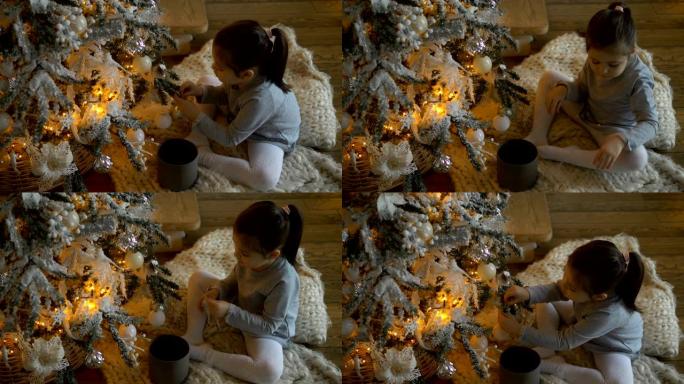 年轻女孩坐在白色格子上，装饰圣诞树