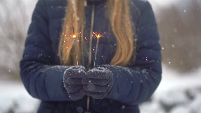 女人在白雪皑皑的背景上手里拿着烟火或孟加拉灯