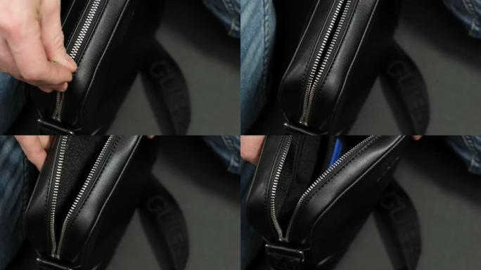 男人的手关闭了黑色手提包上的拉链。特写。