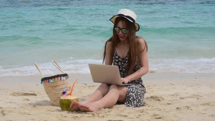 夏天晒黑的女人在海滩上度假。开朗的女人穿着夏装，草帽坐在沙滩上看大海。是时候在夏季放松生活方式户外拍