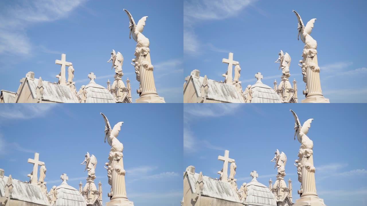墓地墓碑上的天使和十字架。行动。蓝天背景上的白色石雕和十字架塔