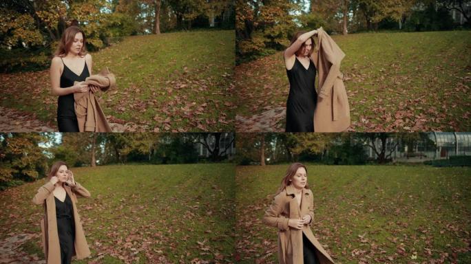 女人走过一个秋天的公园，很冷，穿着棕色外套保暖