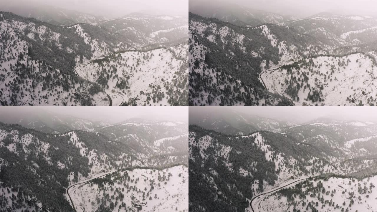 在暴风雪中飞过白雪覆盖的山上。科罗拉多州博尔德外的无人机鸟瞰图。洛矶山脉上方的森林，云层和树木的4k
