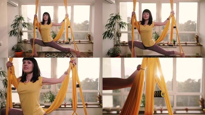 飞行瑜伽。女人在公寓的吊床上做瑜伽练习。