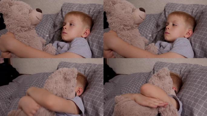 一个患水痘的小男孩和他最喜欢的泰迪熊躺在床上。