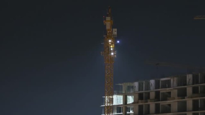 夜间建筑施工。延时。带有照明的建筑工地上的塔式起重机