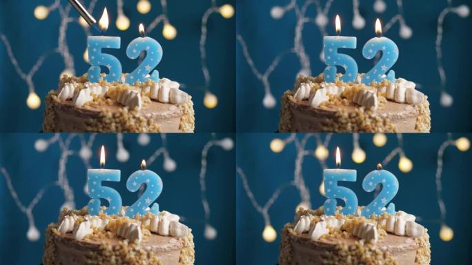 蓝色背景上有52个数字蜡烛的生日蛋糕。蜡烛着火了。慢动作和特写视图