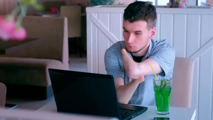 残障残障男子在咖啡馆与残肢在笔记本电脑上视频聊天。
