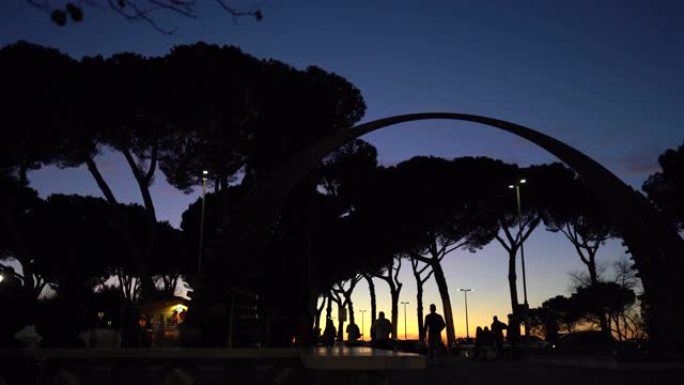 古老的罗马城市称为蒂沃利的傍晚景观。人们剪影走在中央广场上，经过著名的半圆拱门。蒂沃利的日落