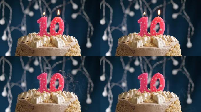 蓝色背景上有10号粉色蜡烛的生日蛋糕。蜡烛吹灭了。慢动作和特写视图