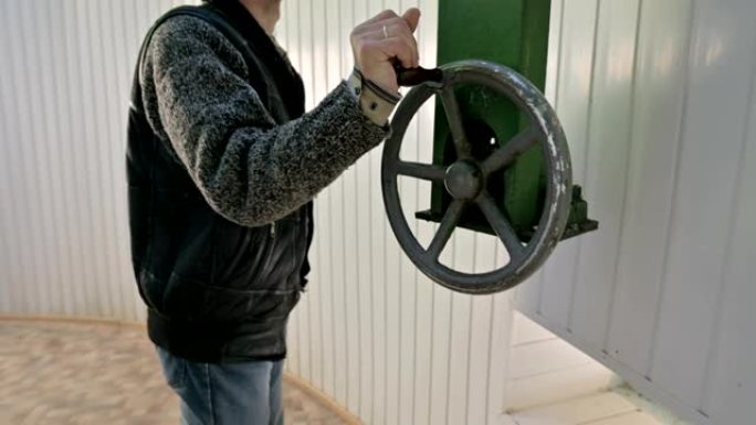 一位男性研究人员旋转太阳天文台圆顶门打开机构的手动轮。高加索山区的科学研究观测站