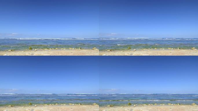低潮期间的岩石海滩，海洋中有小浪，炎热的下午有干净的蓝天