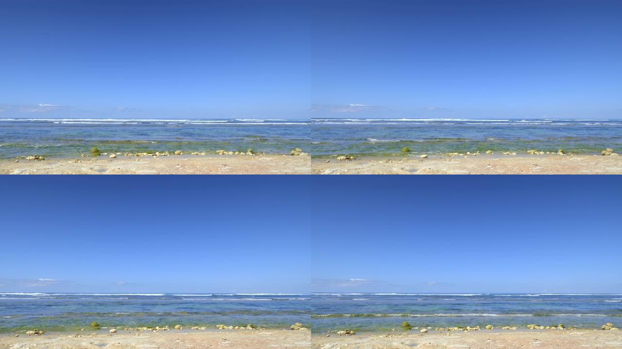 低潮期间的岩石海滩，海洋中有小浪，炎热的下午有干净的蓝天