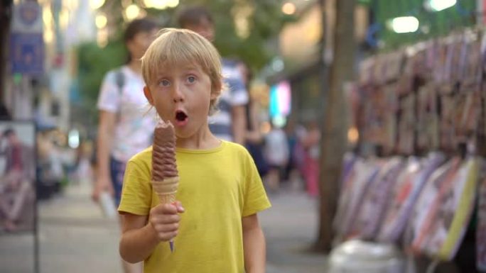 小男孩参观传统的韩国街头市场。男孩正在吃33厘米长的冰激丸。去韩国旅游概念。慢动作镜头