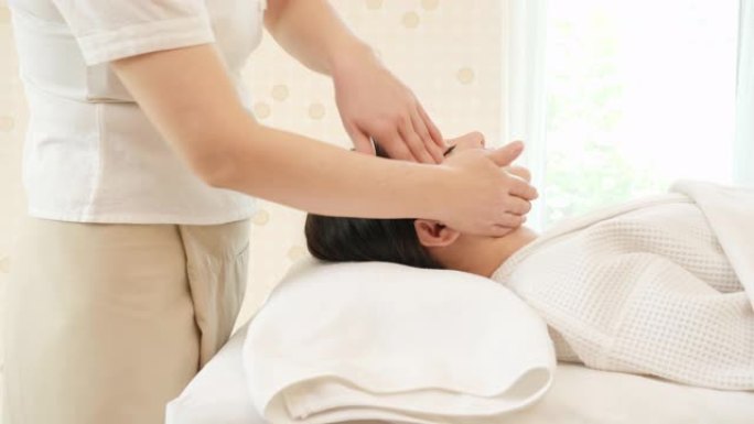 年轻的亚洲女性在美容水疗沙龙接受水疗按摩治疗。面部按摩，放松按摩，水疗皮肤和身体护理。多莉滑块