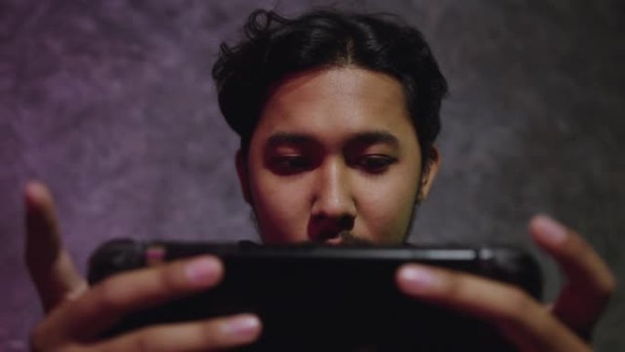 年轻的亚洲男子在卧室里玩控制器的电子游戏