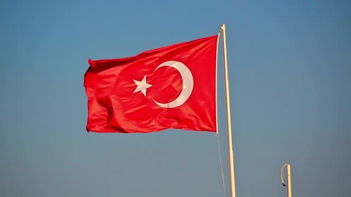 土耳其国旗站在金属柱上，在强烈的夏风中挥舞。