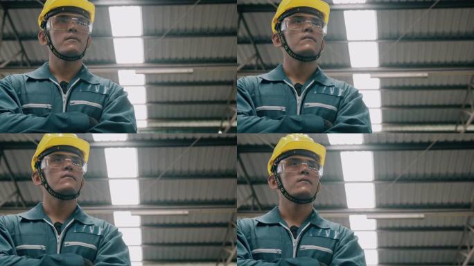 自信的年轻工业工人肖像，双臂交叉，看着相机，抬头看风景。慢动作，亚洲男性，工作服，头盔。工业和制造概