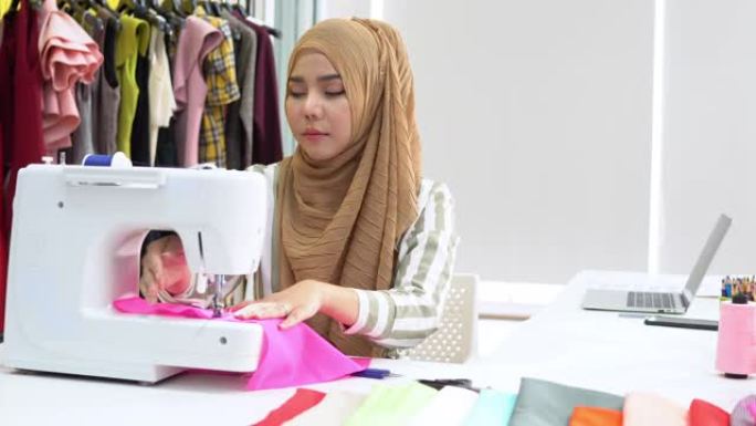 穆斯林妇女时装设计师在家庭工作室的电动缝纫机上纺织，潘射击