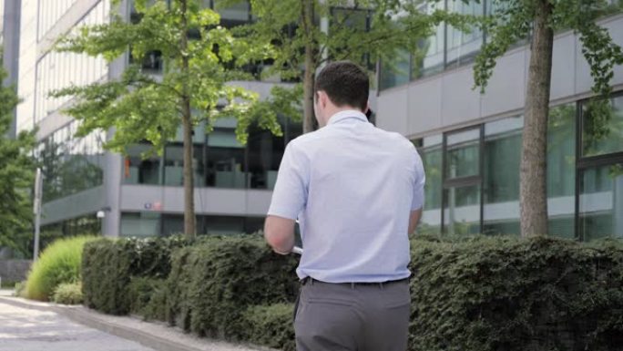 男人在电话上-年轻商人穿着智能休闲装走路时使用智能手机