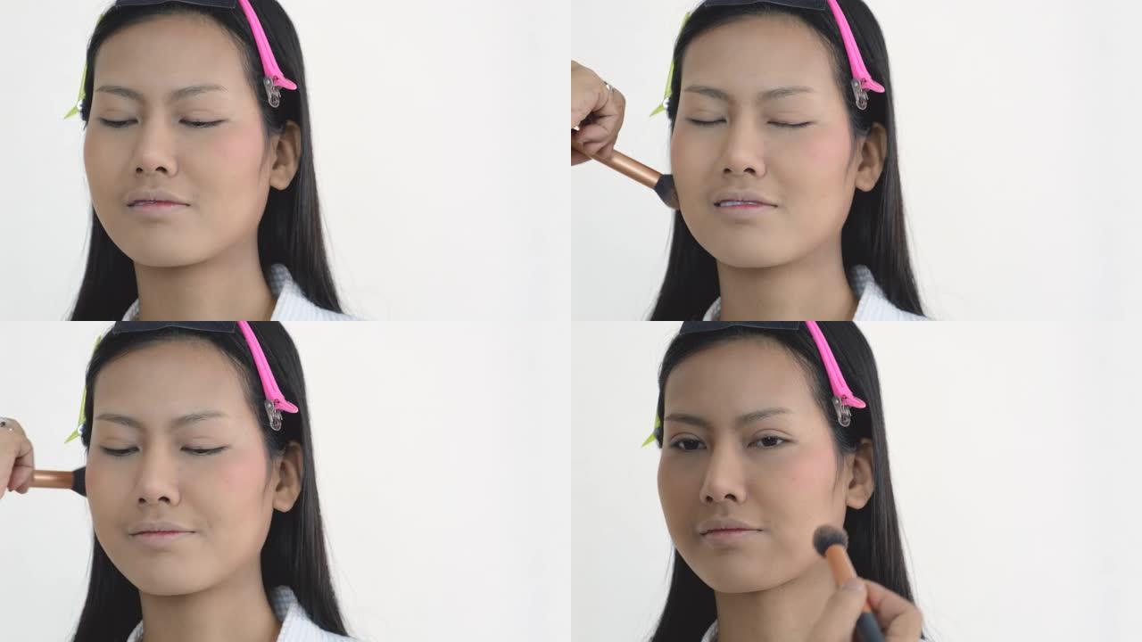 化妆师用白色背景的刷子向美女展示脸颊区域的化妆过程