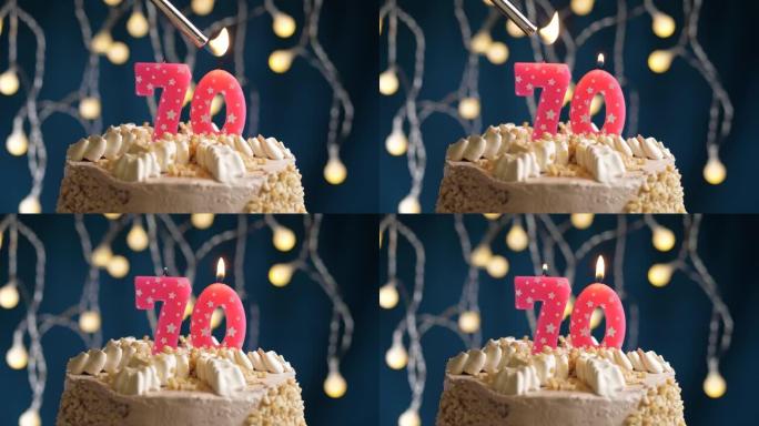 蓝色背景上有70号粉色蜡烛的生日蛋糕。蜡烛着火了。慢动作和特写视图