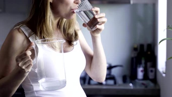 美女孕妇在玻璃杯里倒水喝