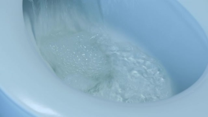 男性手在白色马桶冲尿，特写。灰色瓷砖浴室白色卫生间侧视图。水冲入浴室的马桶。马桶里的水被冲洗了