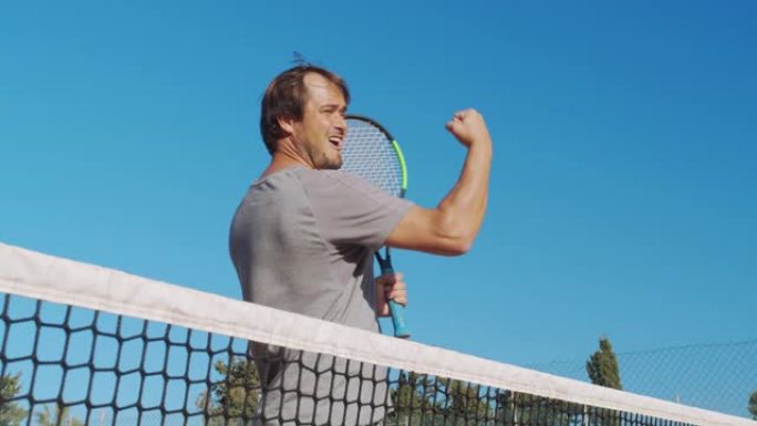 在室外硬地球场打网球的男运动员。快乐的人庆祝成功和胜利