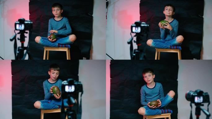 一个男孩坐在摄像机前，拿着芒果